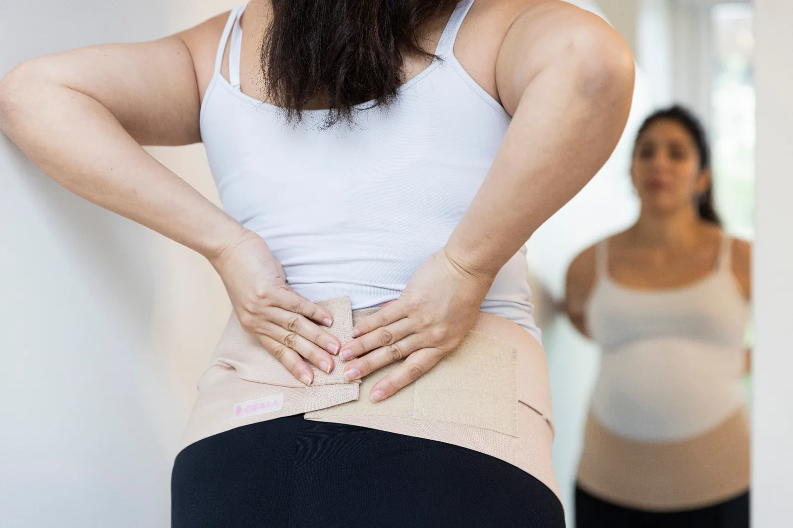 Mujer ajustándose la faja DEMA en la zona lumbar
